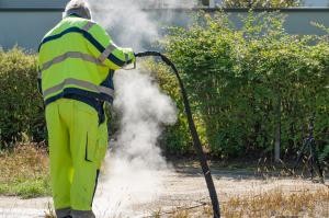 Ein Betriebshofmitarbeiter leitet heißes Wasser in den Erdboden ein.