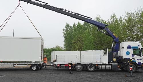 Kälteschutz 2025 mit einem Kran wird ein Container auf die Ladefläche eines Lastkraftwagens gehievt.