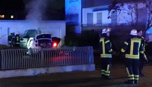 Autobrand Feuerwehrleute untersuchen ein dampfendes Auto